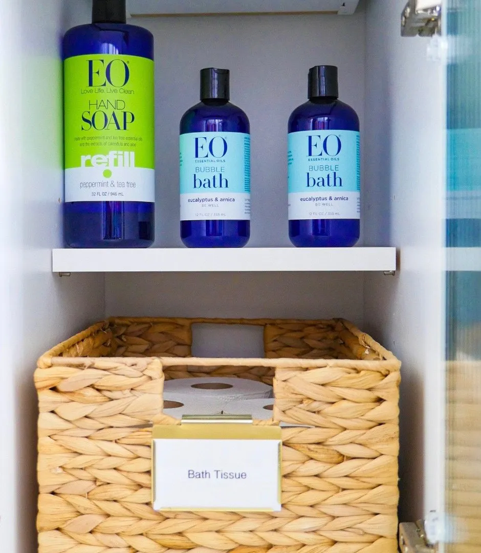 A bathroom cabinet with a labeled basket